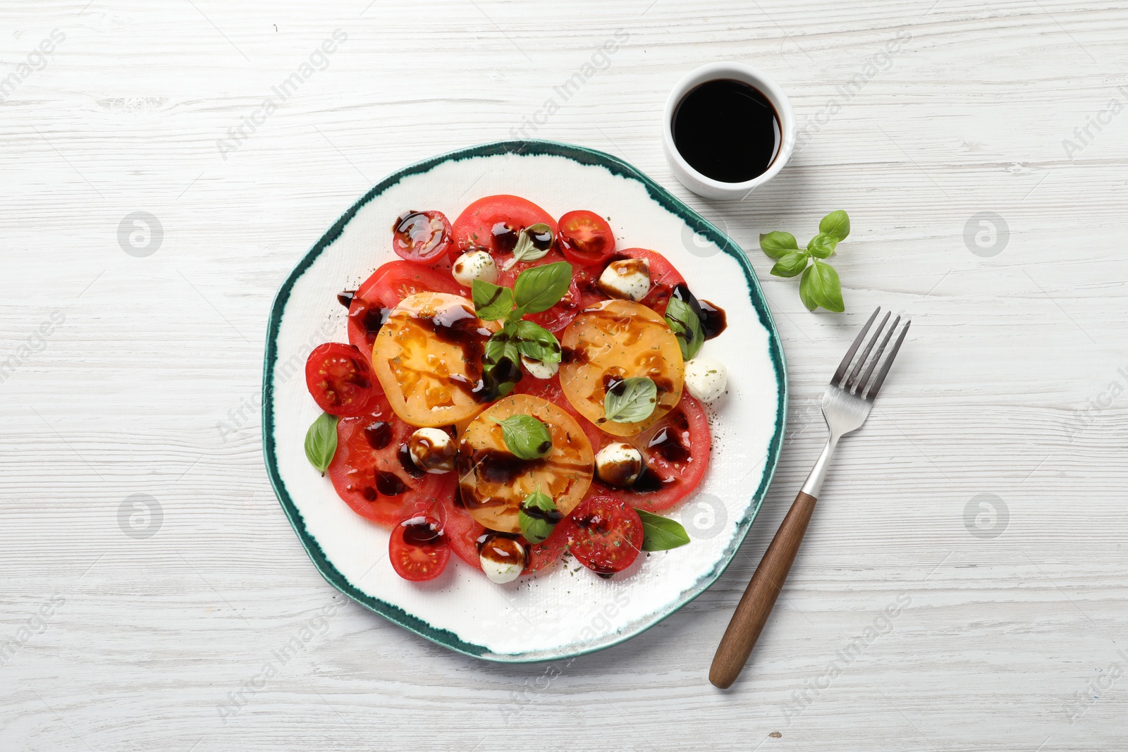 Photo of Tasty salad with balsamic vinegar and mozzarella on white wooden table, top view