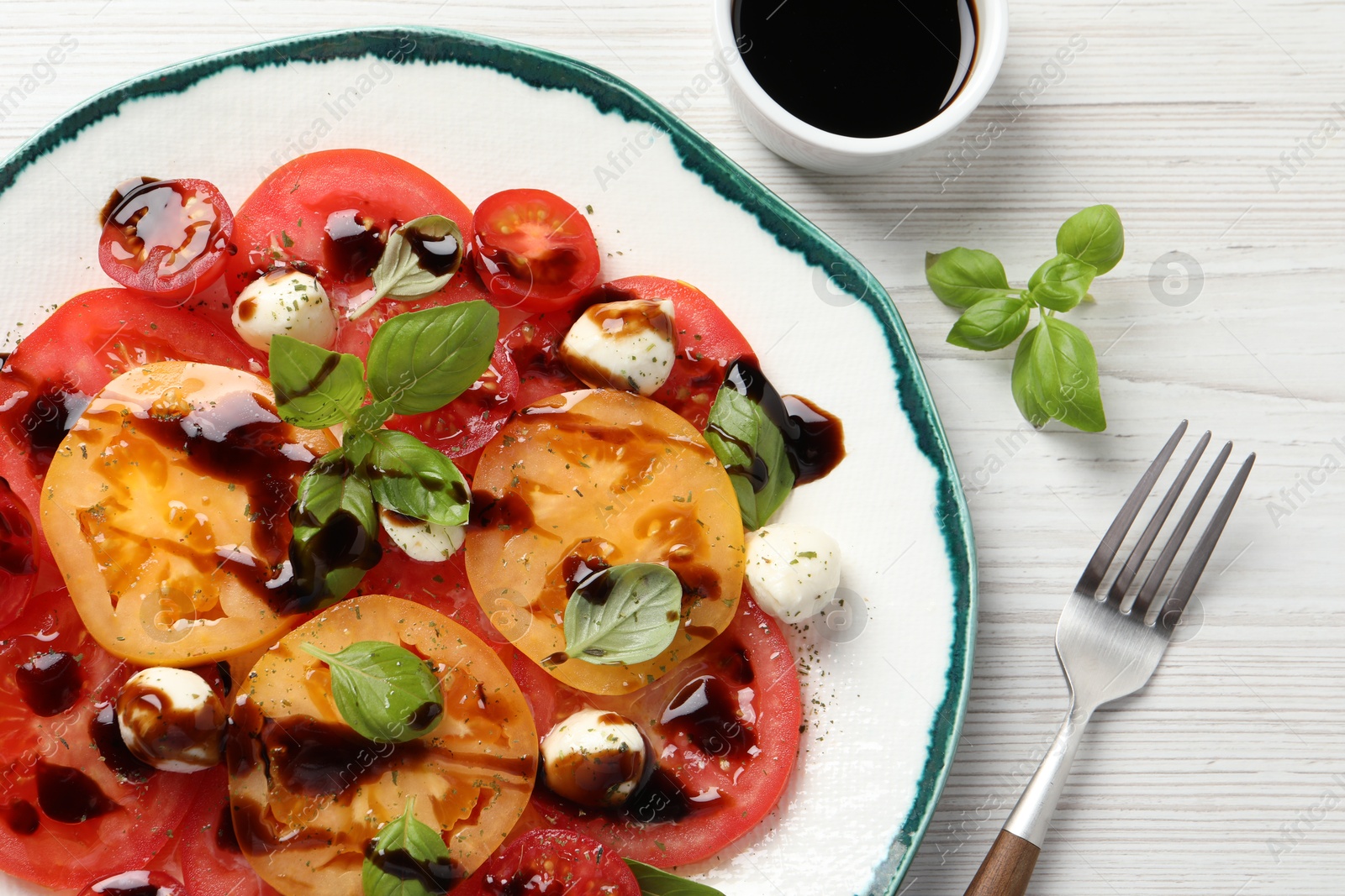 Photo of Tasty salad with balsamic vinegar and mozzarella on white wooden table, top view