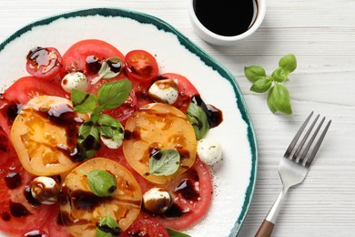 Tasty salad with balsamic vinegar and mozzarella on white wooden table, top view