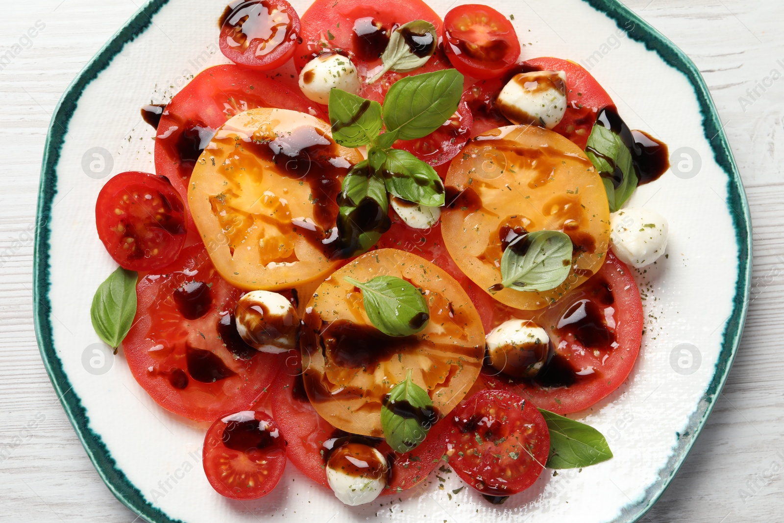 Photo of Tasty salad with balsamic vinegar and mozzarella on white wooden table, top view