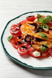 Tasty salad with balsamic vinegar and mozzarella on white wooden table, closeup