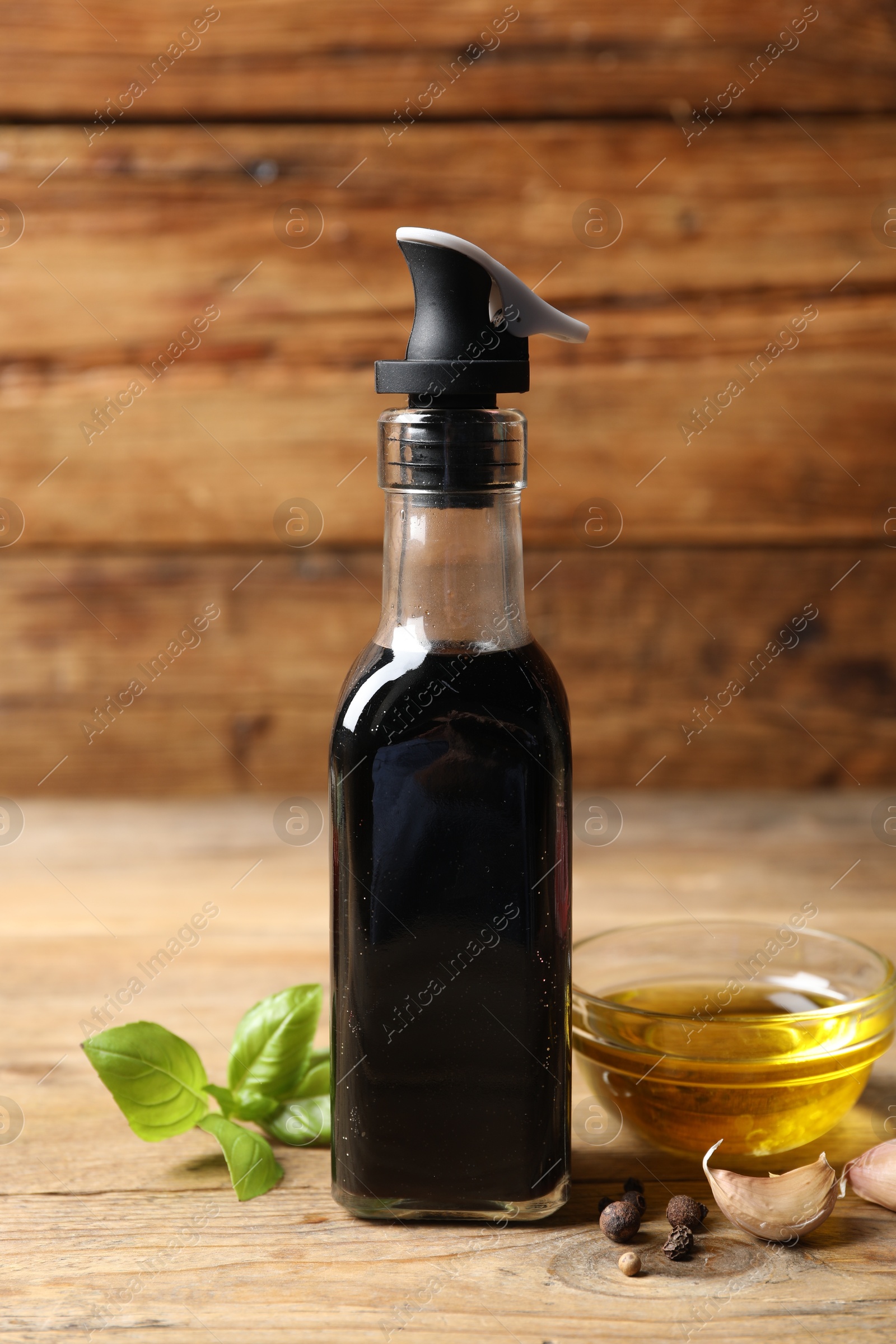 Photo of Bottle of balsamic vinegar, oil and other products on wooden table