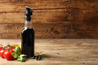 Photo of Bottle of balsamic vinegar, oil and other products on wooden table, space for text