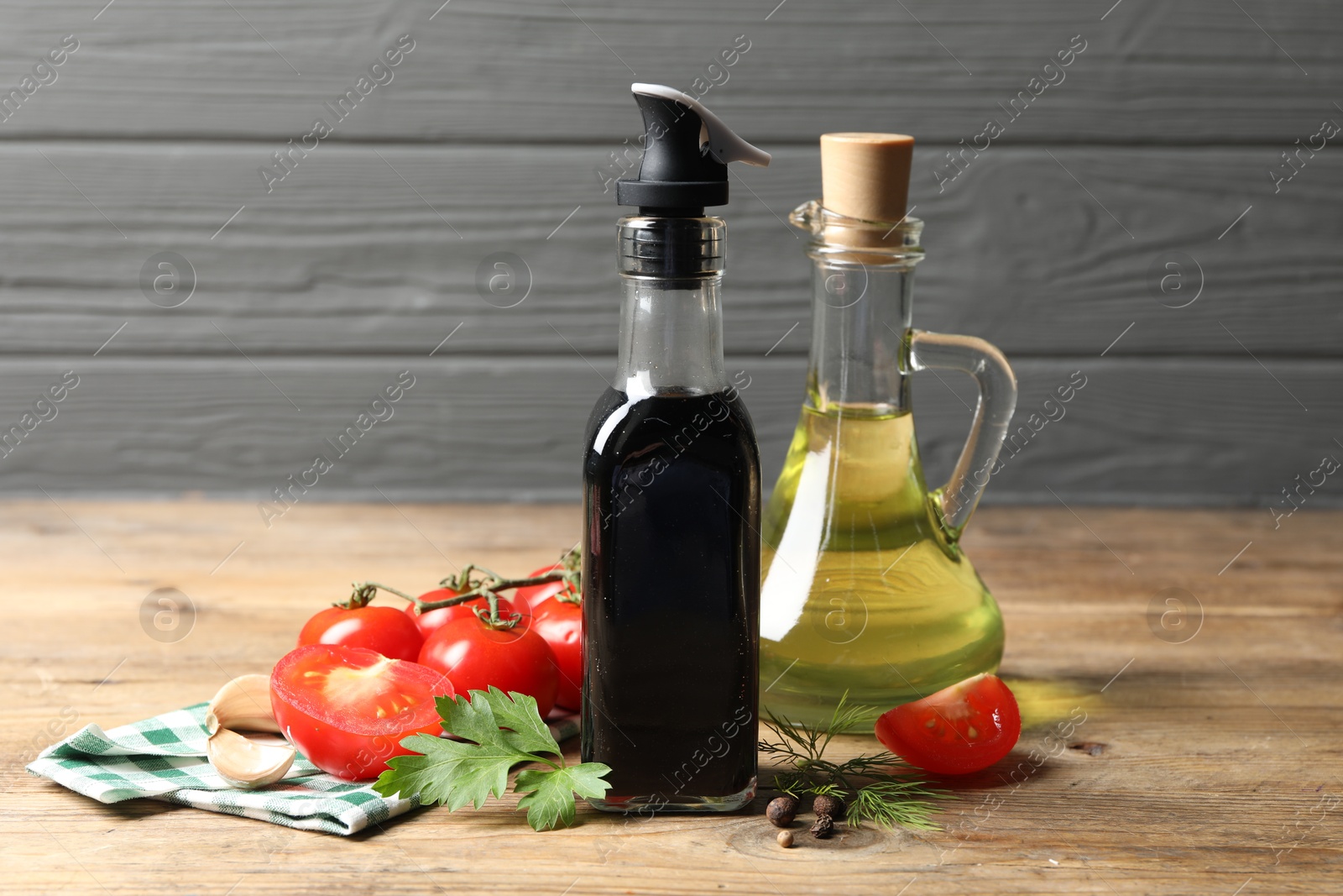 Photo of Bottle of balsamic vinegar, oil and other products on wooden table