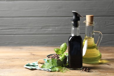 Photo of Bottle of balsamic vinegar, oil and other products on wooden table, space for text