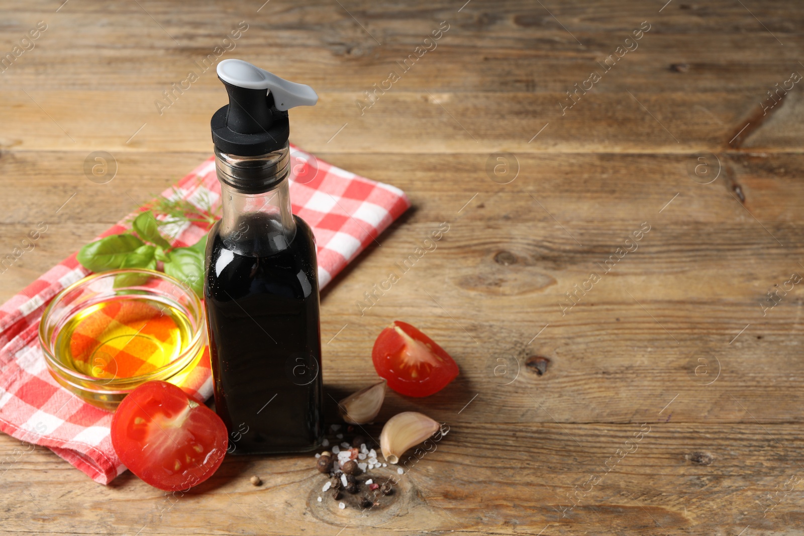 Photo of Bottle of balsamic vinegar, oil and other products on wooden table, space for text