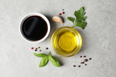 Photo of Balsamic vinegar, oil and other products on light grey table, flat lay