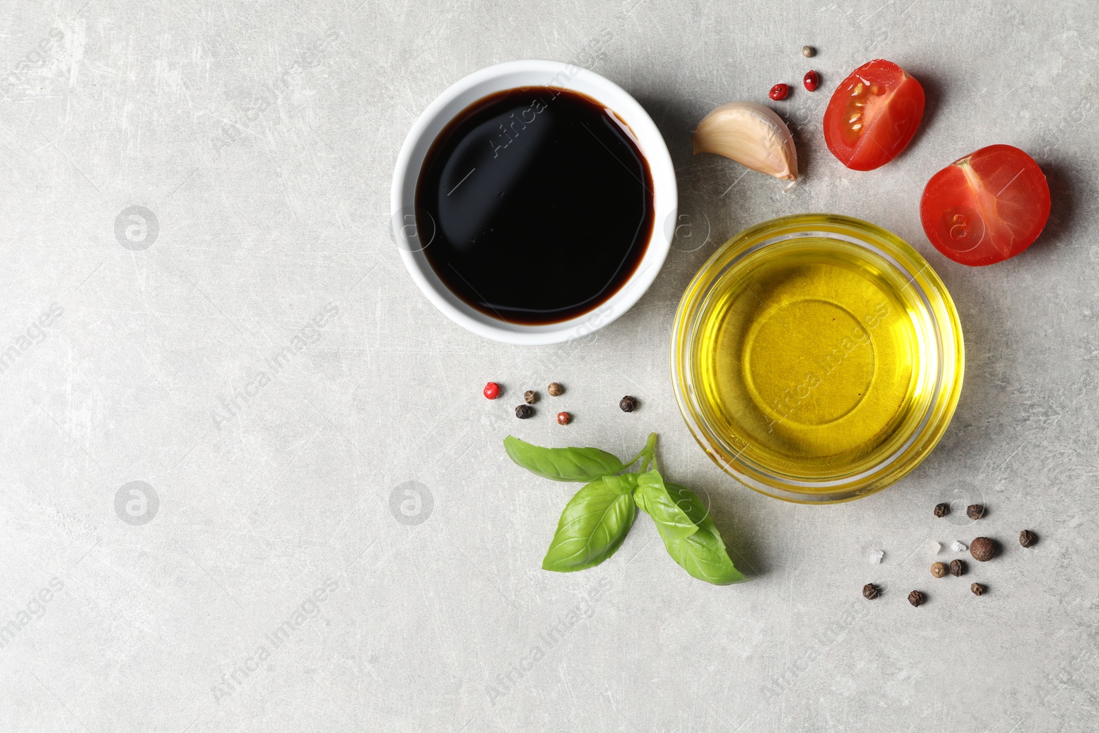 Photo of Balsamic vinegar, oil and other products on light grey table, flat lay. Space for text