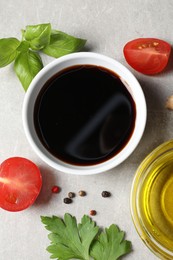 Photo of Balsamic vinegar, oil and other products on light grey table, flat lay