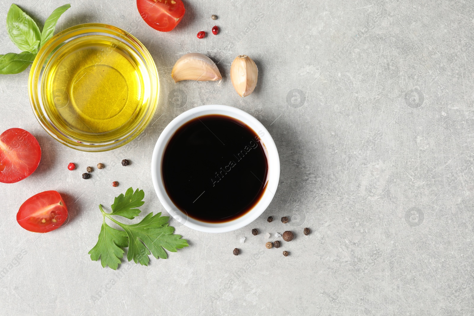 Photo of Balsamic vinegar, oil and other products on light grey table, flat lay. Space for text