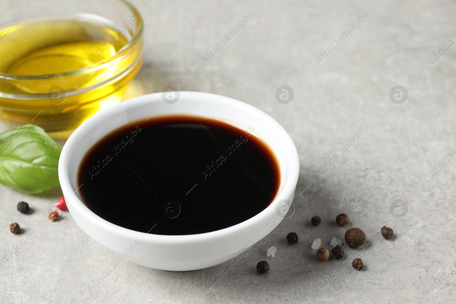 Photo of Balsamic vinegar, oil and peppercorns on light grey table, closeup. Space for text