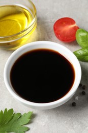 Photo of Balsamic vinegar, oil and other products on light grey table, closeup