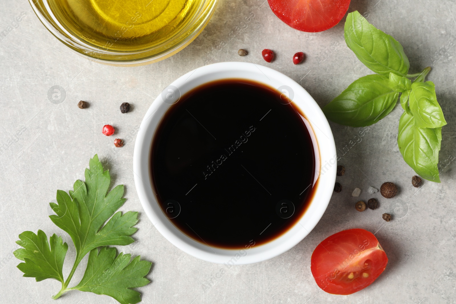 Photo of Balsamic vinegar, oil and other products on light grey table, flat lay