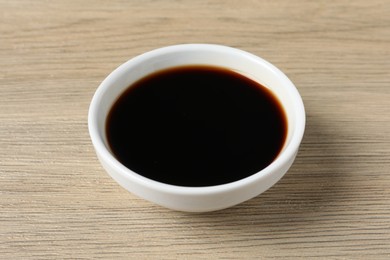 Photo of Balsamic vinegar in bowl on light wooden table