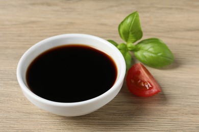 Balsamic vinegar, tomato and basil on light wooden table