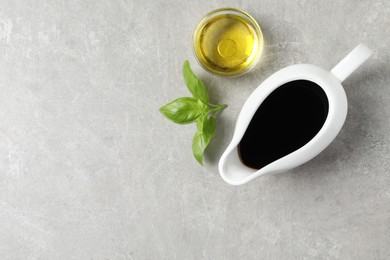 Balsamic vinegar, oil and basil on light grey table, flat lay. Space for text