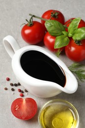 Photo of Balsamic vinegar, oil and other products on light grey table