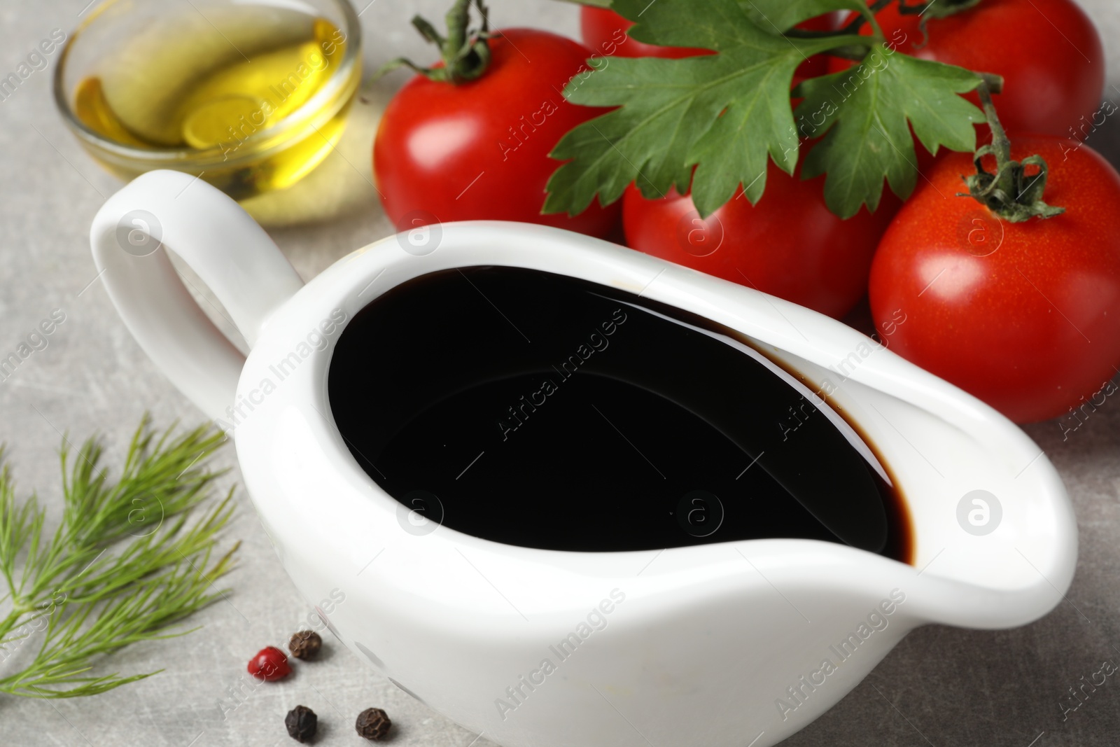 Photo of Balsamic vinegar, oil and other products on light grey table, closeup