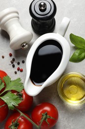 Photo of Balsamic vinegar, oil and other products on light grey table, flat lay