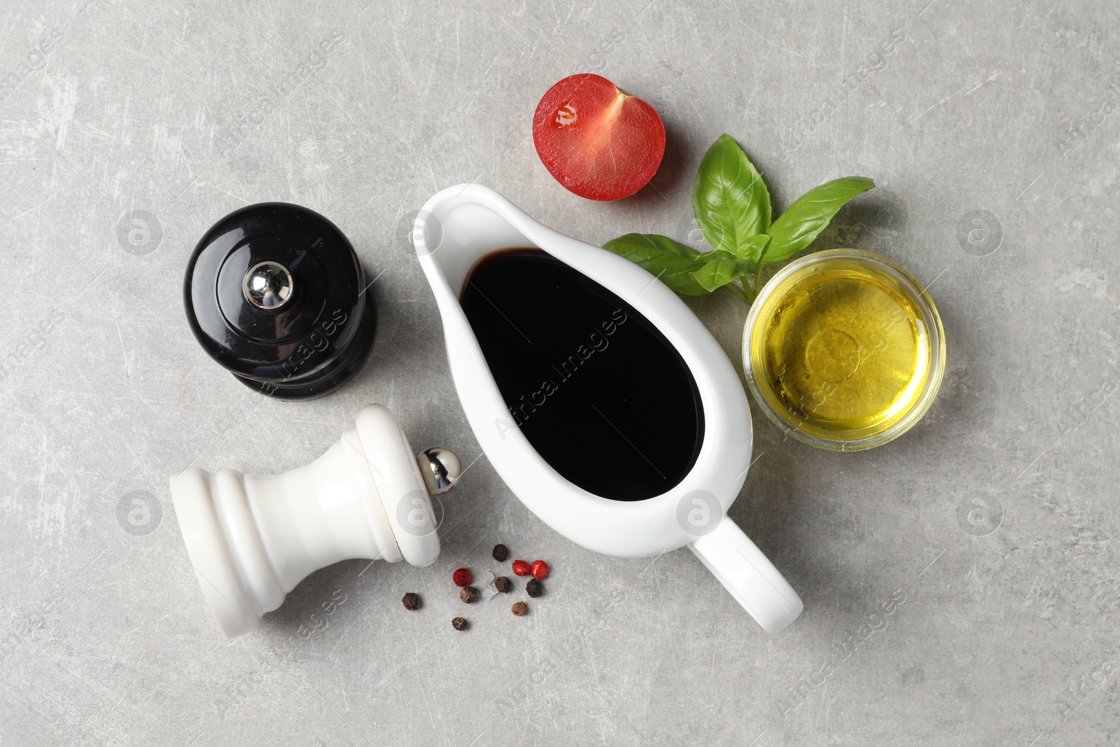 Photo of Balsamic vinegar, oil and other products on light grey table, flat lay