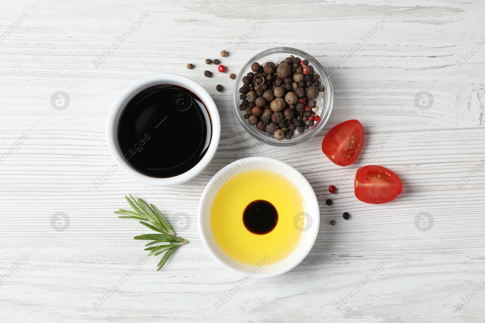 Photo of Balsamic vinegar, oil and other products on white wooden table, flat lay