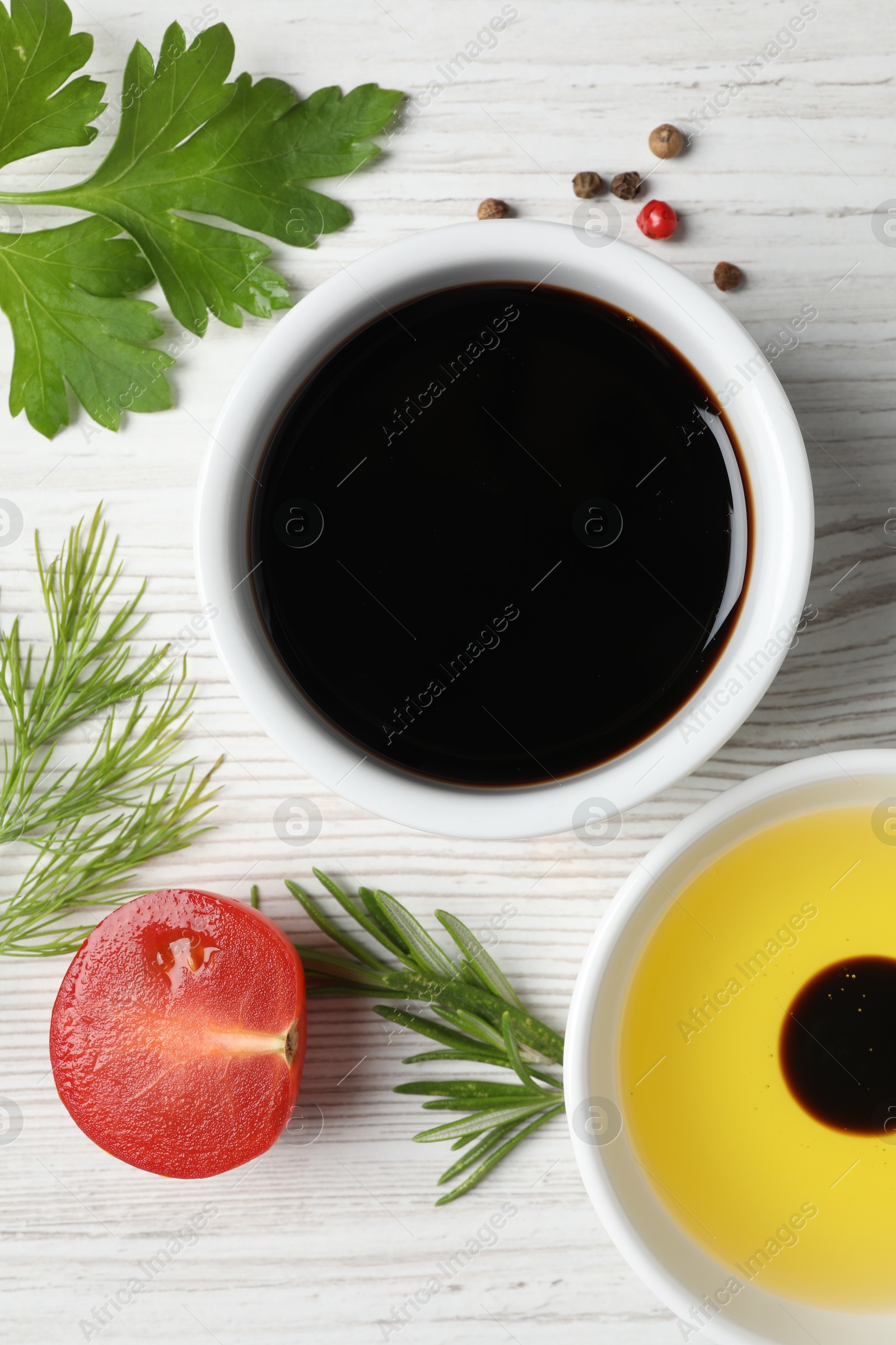 Photo of Balsamic vinegar, oil and other products on white wooden table, flat lay