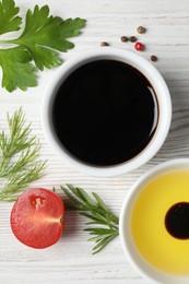 Photo of Balsamic vinegar, oil and other products on white wooden table, flat lay