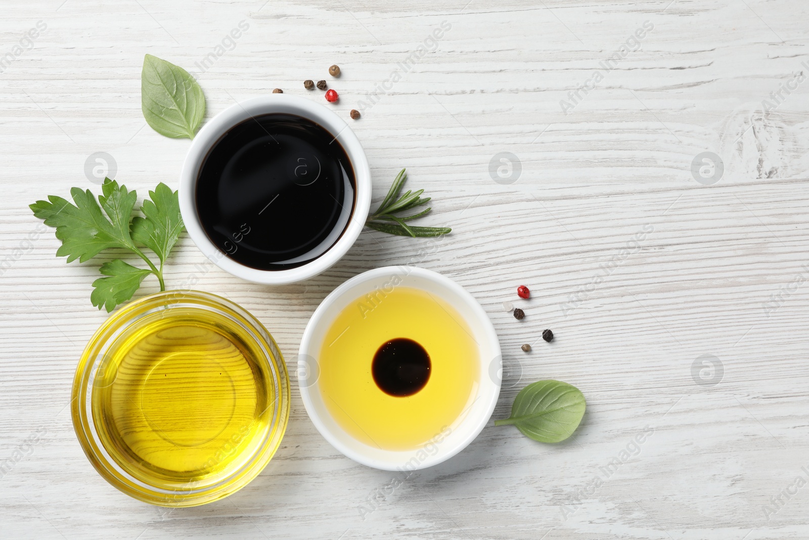 Photo of Balsamic vinegar, oil and other products on white wooden table, flat lay. Space for text