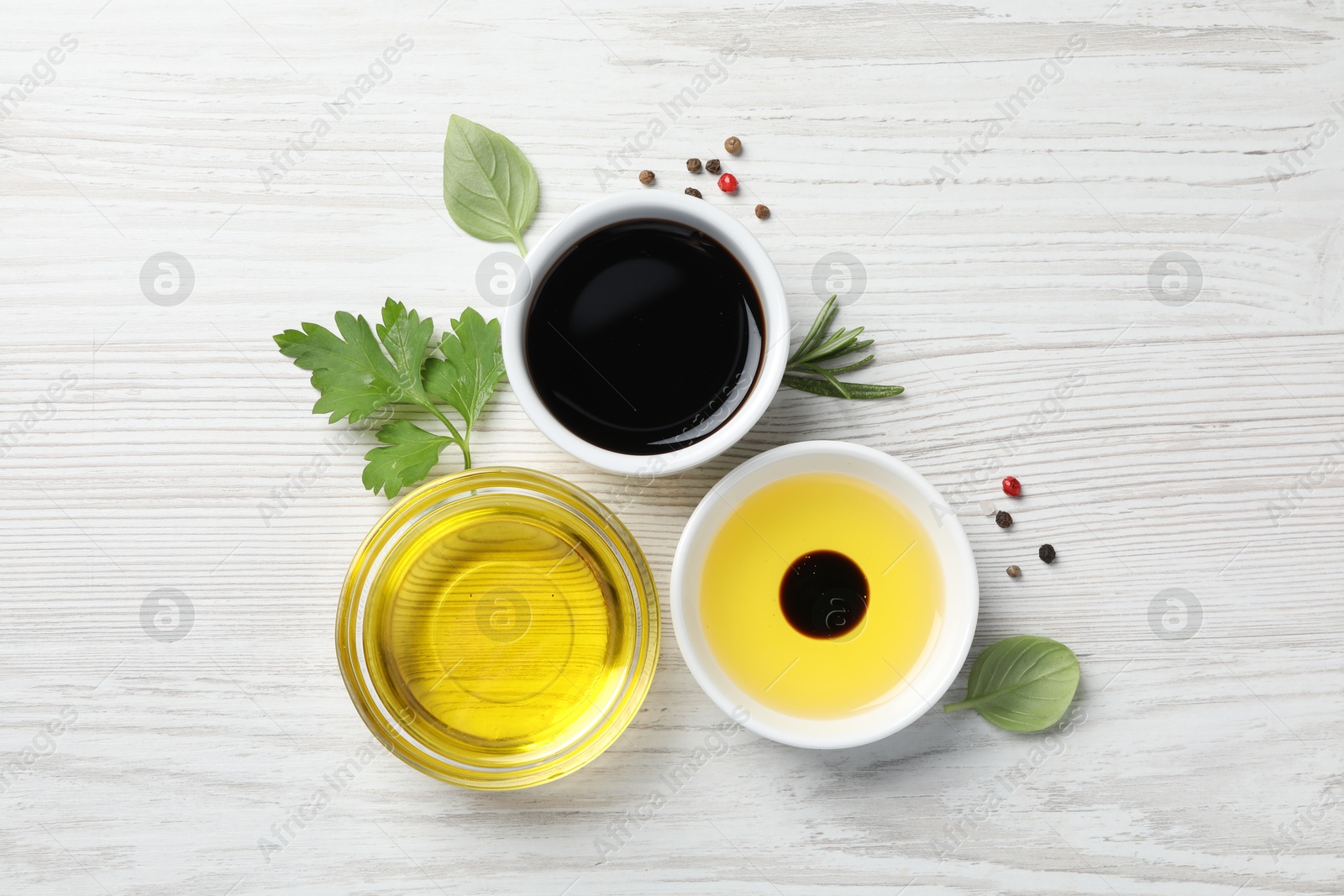 Photo of Balsamic vinegar, oil and other products on white wooden table, flat lay