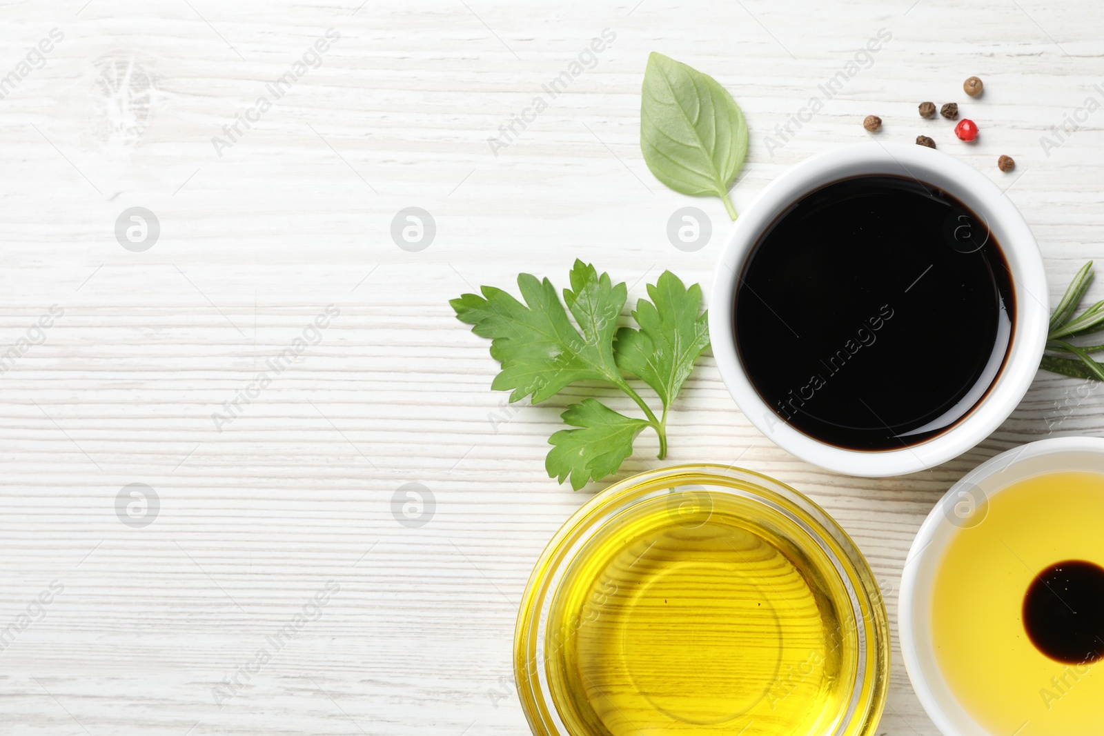 Photo of Balsamic vinegar, oil and other products on white wooden table, flat lay. Space for text