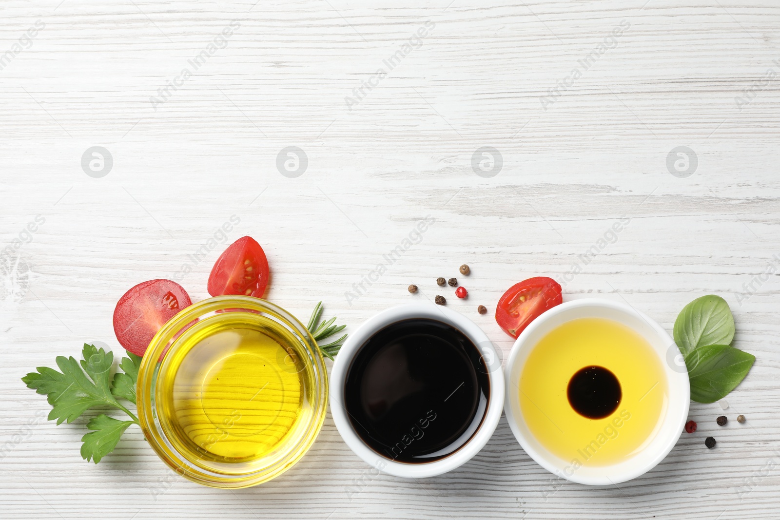 Photo of Balsamic vinegar, oil and other products on white wooden table, flat lay. Space for text