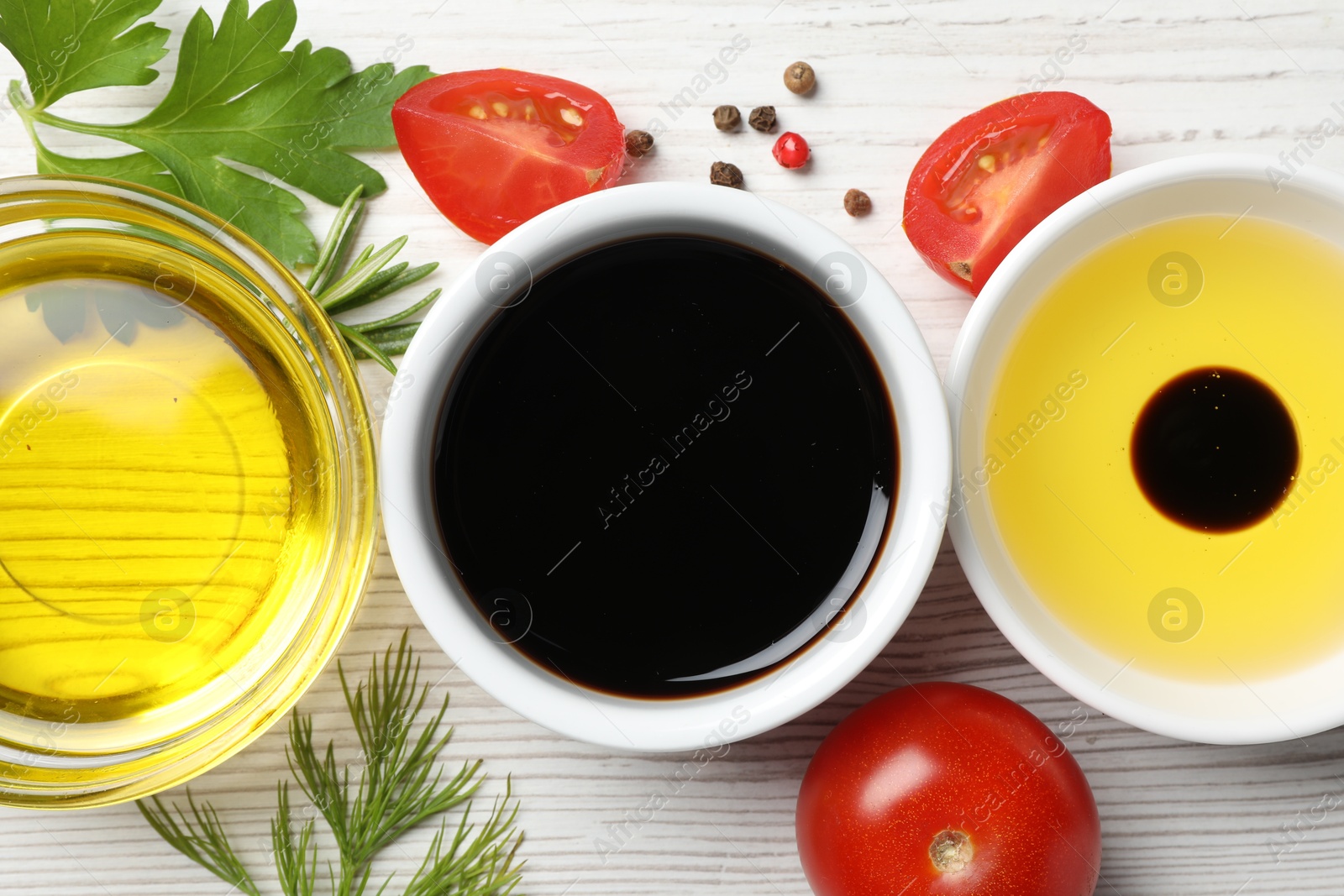 Photo of Balsamic vinegar, oil and other products on white wooden table, flat lay