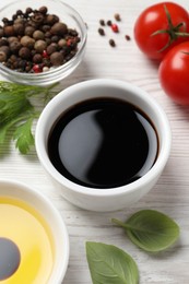 Photo of Balsamic vinegar, oil and other products on white wooden table