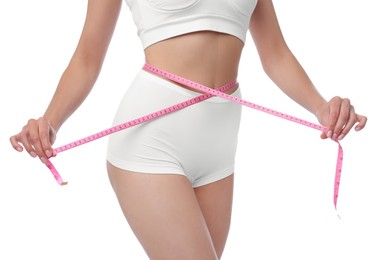 Diet and weight loss concept. Woman with measuring tape showing her slim body against white background, closeup