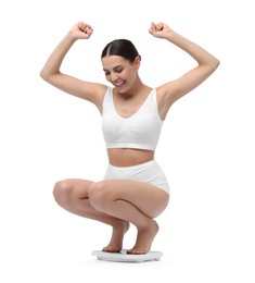 Photo of Diet and weight loss concept. Happy young woman on floor scale against white background