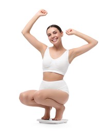 Photo of Diet and weight loss concept. Happy young woman on floor scale against white background