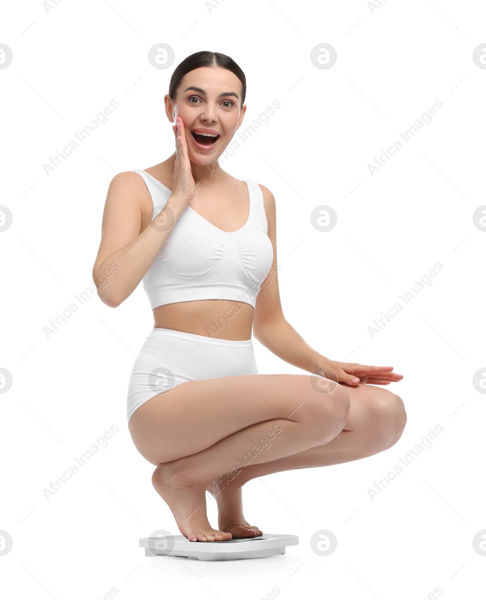 Photo of Diet and weight loss concept. Happy young woman on floor scale against white background