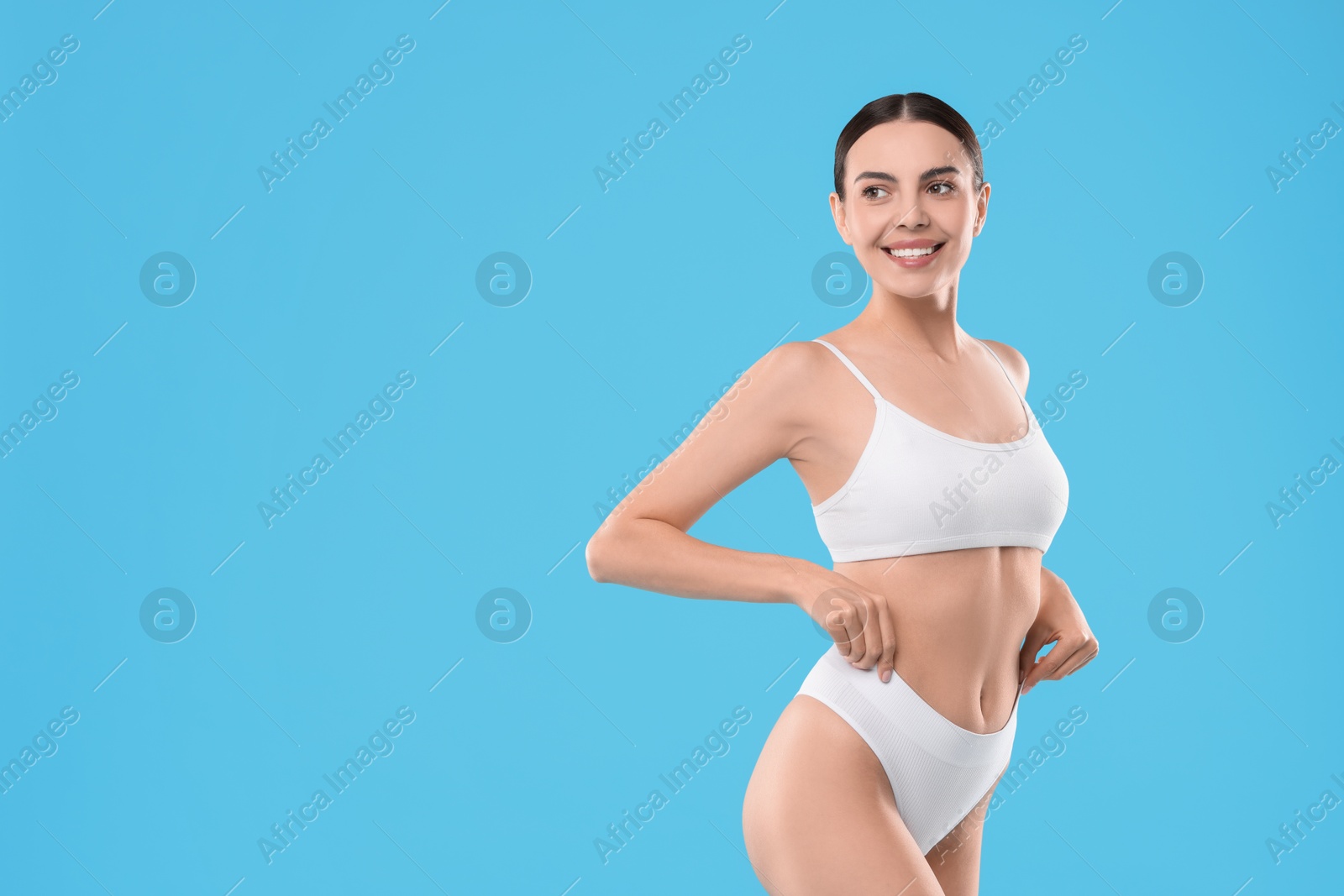 Photo of Diet and weight loss concept. Beautiful young woman with slim body against light blue background. Space for text