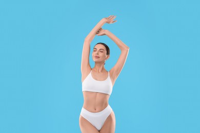 Diet and weight loss concept. Beautiful young woman with slim body against light blue background