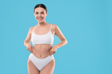 Photo of Diet and weight loss concept. Beautiful young woman with slim body against light blue background. Space for text