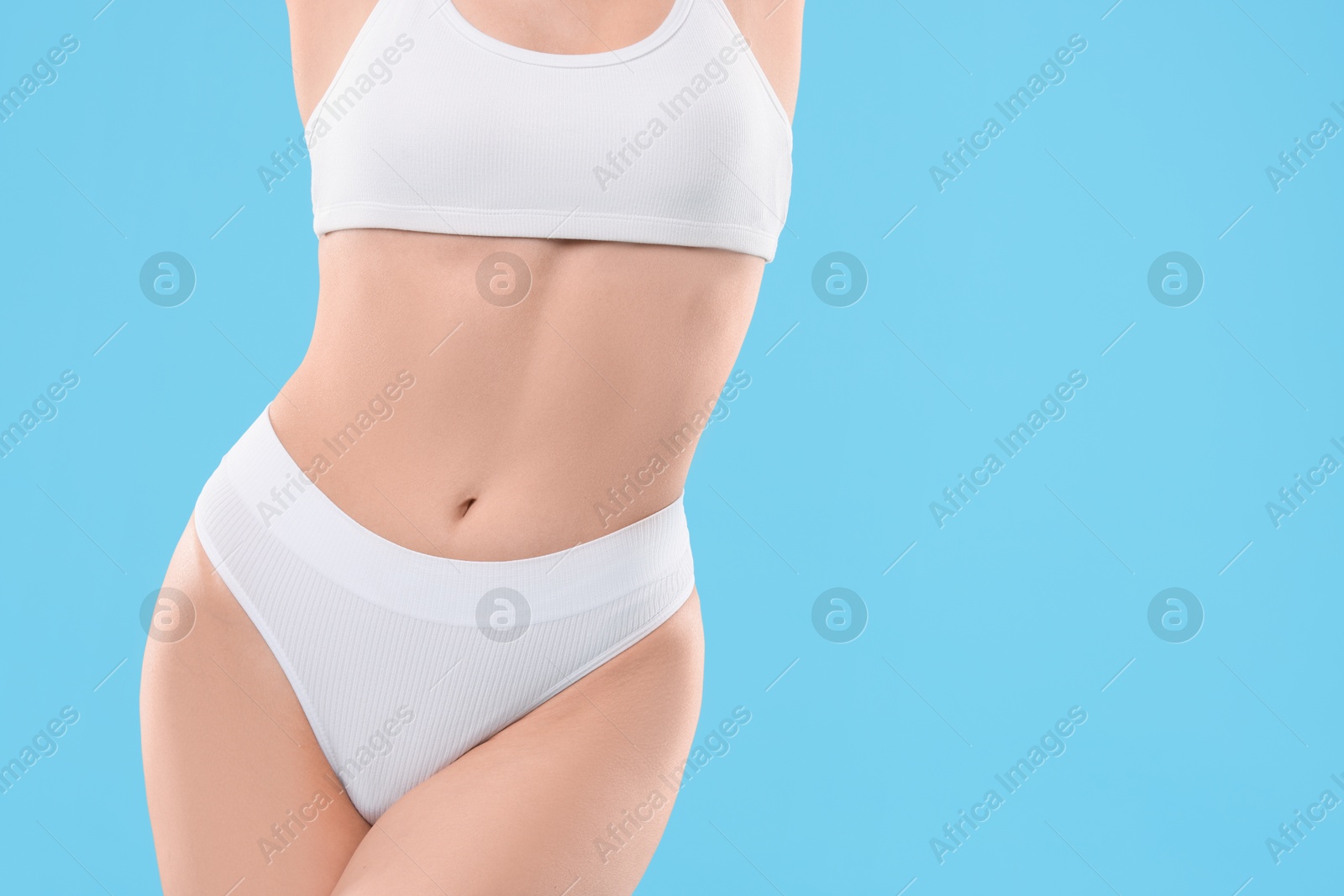 Photo of Diet and weight loss concept. Woman with slim body against light blue background, closeup. Space for text