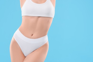 Photo of Diet and weight loss concept. Woman with slim body against light blue background, closeup. Space for text