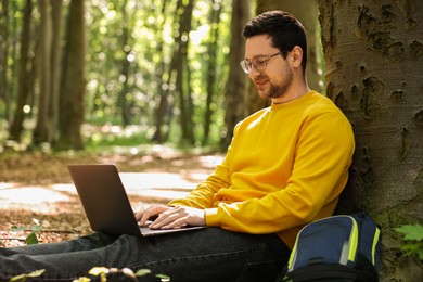 Smiling traveler working with laptop outdoors. Remote job