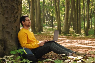 Smiling traveler working with laptop outdoors. Remote job