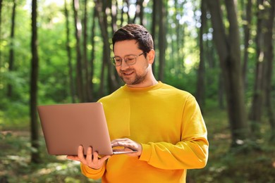 Smiling traveler working with laptop outdoors on sunny day. Remote job