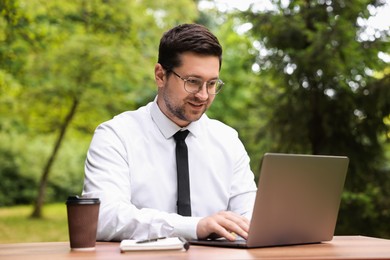 Photo of Businessman working with laptop at table outdoors. Remote job