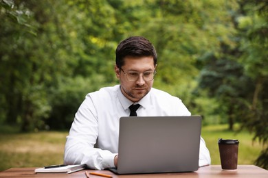 Photo of Businessman working with laptop at table outdoors. Remote job