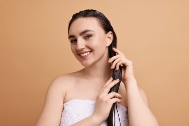 Photo of Smiling woman applying hair mask on beige background