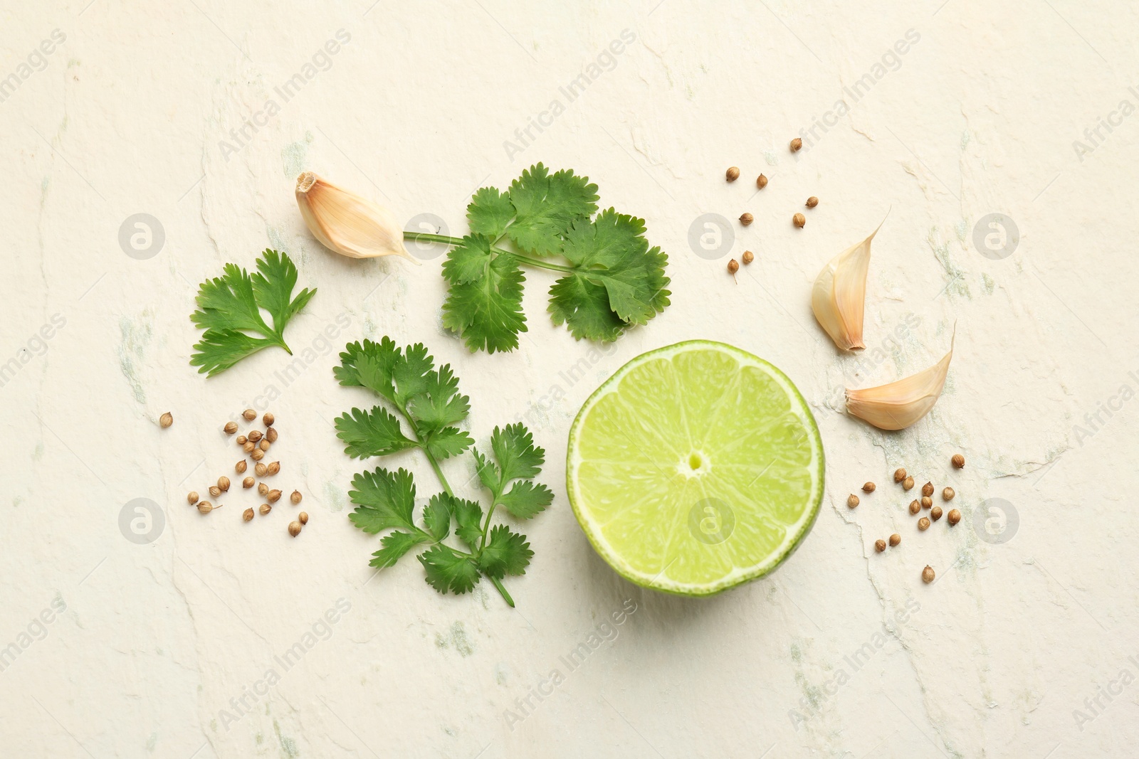 Photo of Fresh coriander leaves, dried seeds, garlic and lime on light textured table, flat lay