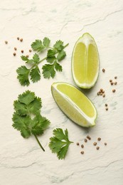 Fresh coriander leaves, dried seeds and lime wedges on light textured table, flat lay